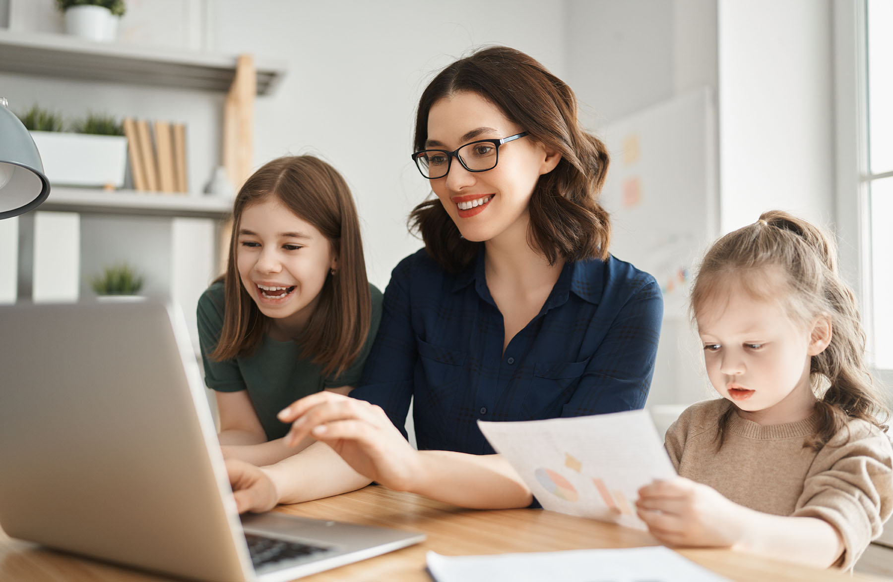 Young mother with children working on the computer. Family at home. Remote work.